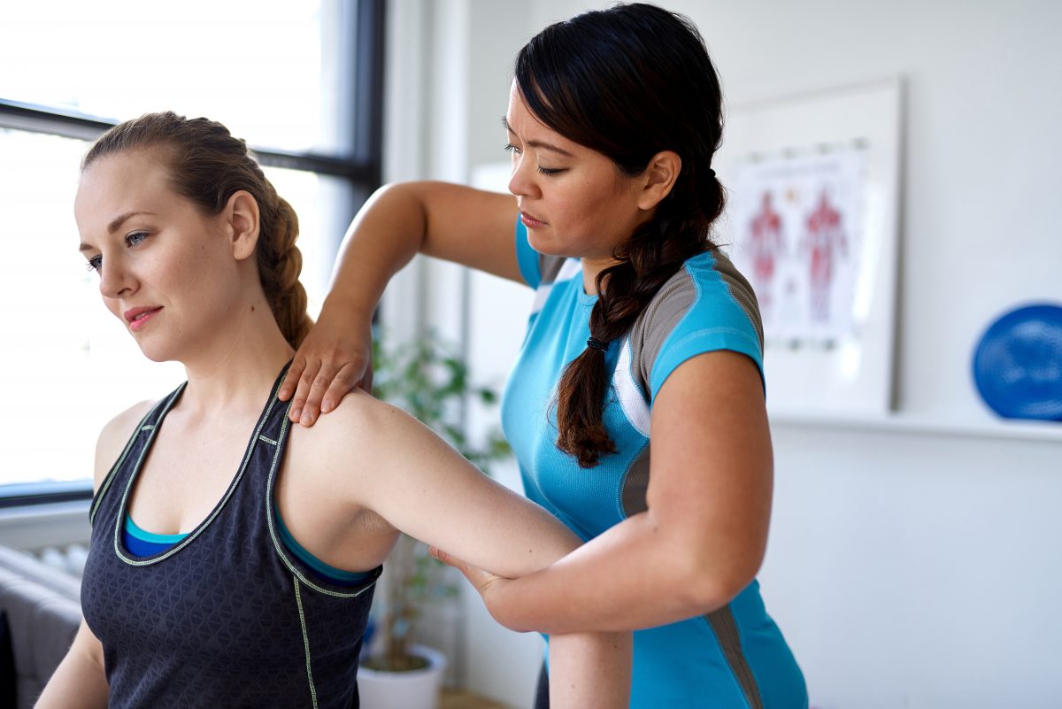 Physiotherapy professional giving a treatment to a client in a bright medical office