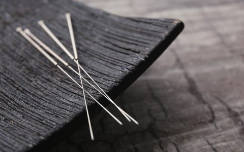 Needles for acupuncture and special stand on grey background, closeup